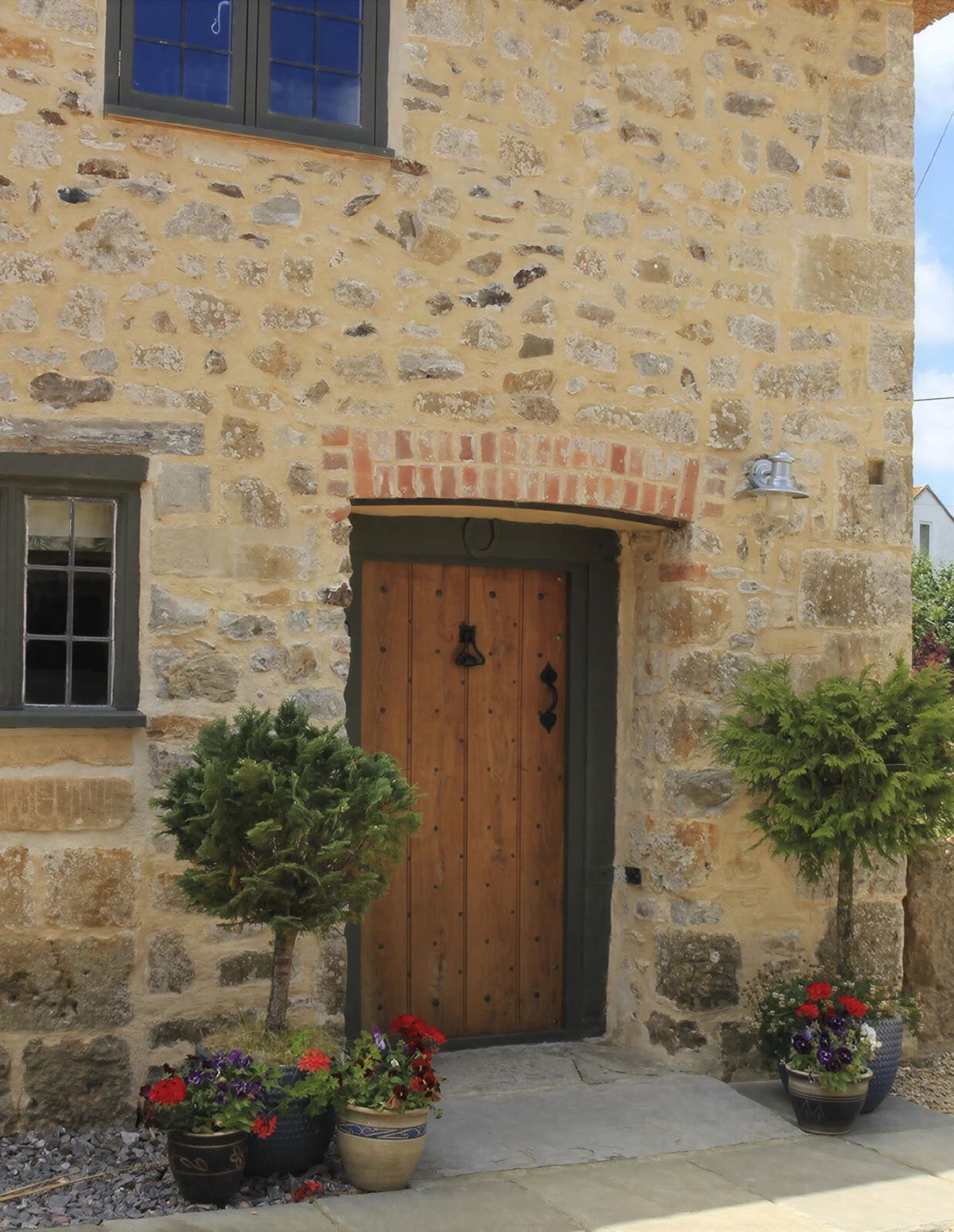 Un bâtiment en pierre avec une porte en bois, une fenêtre et des plantes en pot.