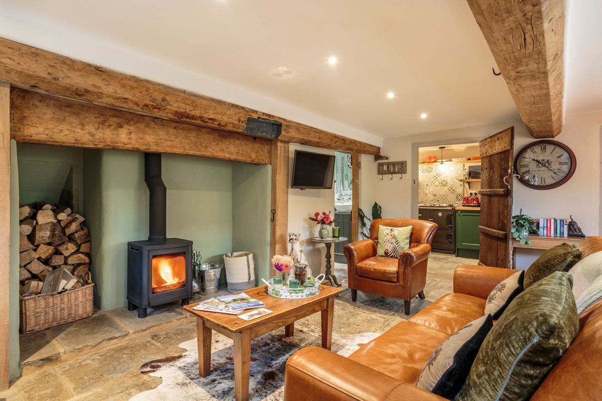 A cozy living room with a fireplace, leather sofa, and a dining area.