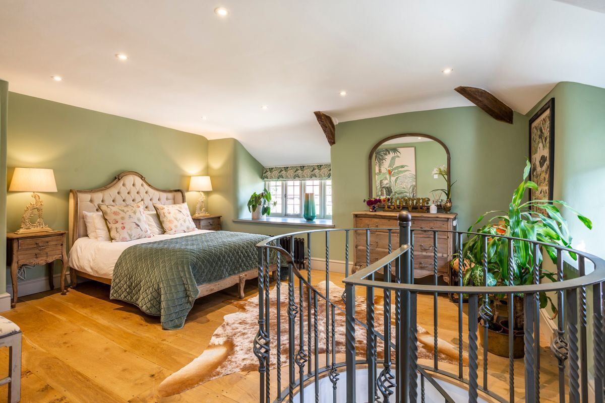 Une chambre à coucher avec un lit, une commode, un miroir et un escalier.