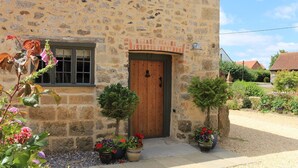 A stone building with a wooden door, potted plants, and a window.