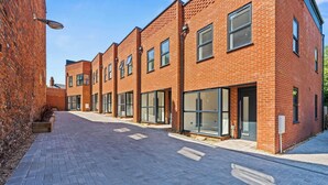A row of modern brick buildings with large windows and a paved walkway. - New Central House | Contractor & Family Friendly (Reading)