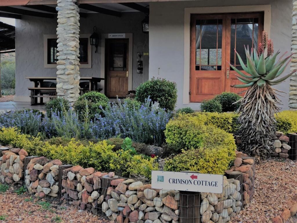A stone pillar, a wooden door, and a sign for Crimson Cottage.