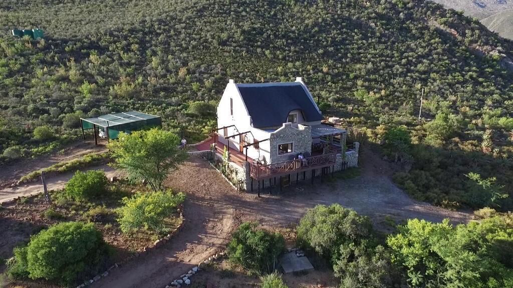 A house with a large deck, surrounded by a natural landscape.