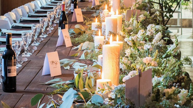 A long table set for a formal event with candles, wine bottles, and floral arrangements. - Oaksrest Vineyards Guest Farm (Ladismith)
