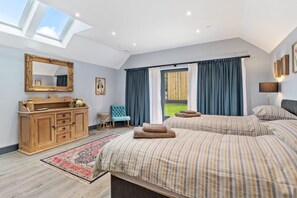 A bedroom with two beds, a wooden dresser, a mirror, and a skylight. - Cardigan Courtyard - Five Bedroom Villa, Sleeps 10 (Tan-y-groes)