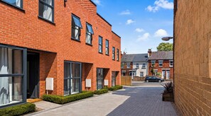 A modern brick building with large windows and a paved driveway. - Brand New Modern House Near Reading Town Center (Reading)