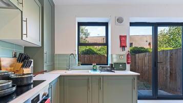 A modern kitchen with a large window, a fire blanket, and a first aid kit.