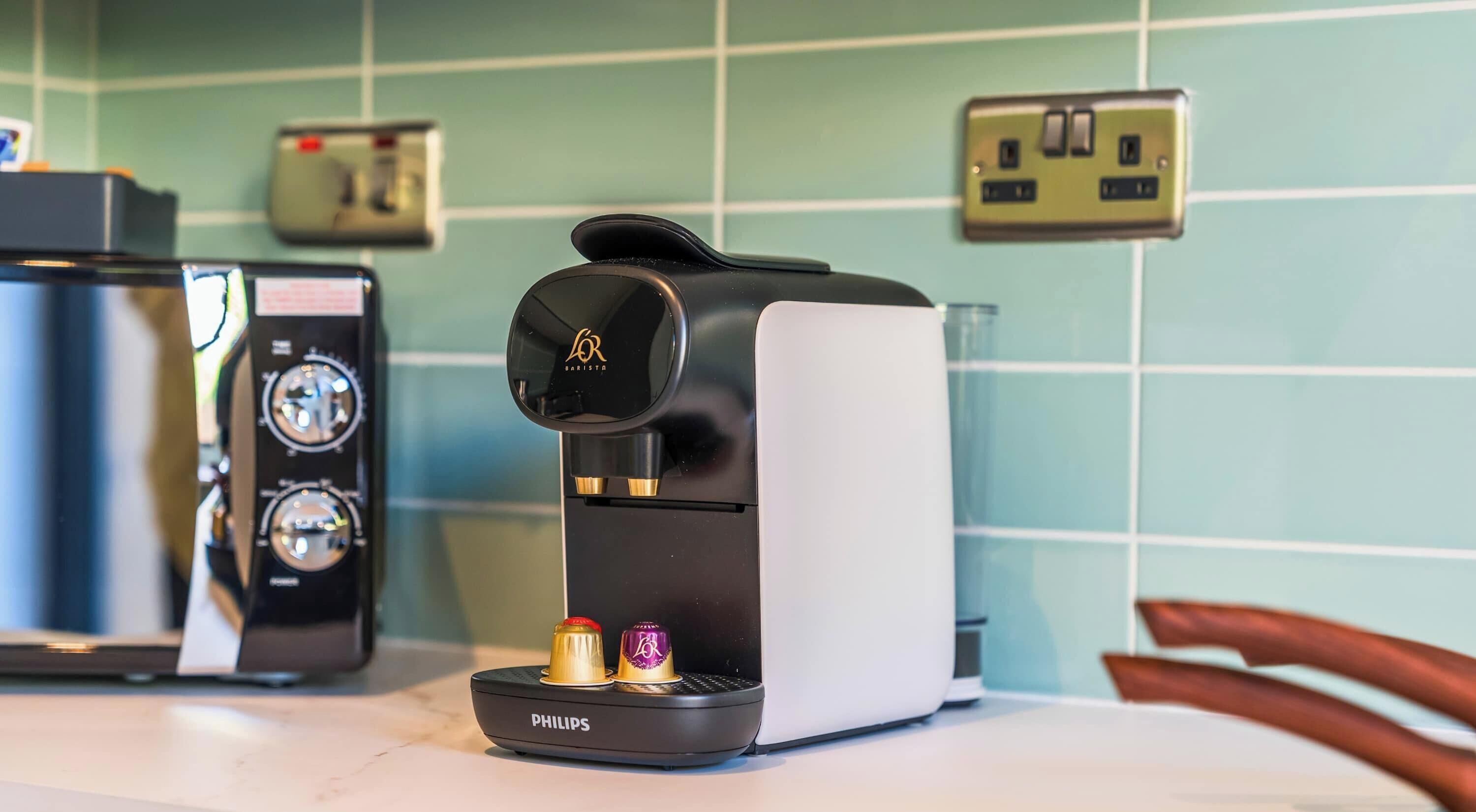 Una cafetera con pantalla digital, un tostador y una tetera sobre una encimera de cocina.