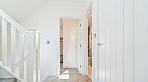 Ein Flur mit Teppichboden, weißen Wänden und einer Tür zu einem Badezimmer.