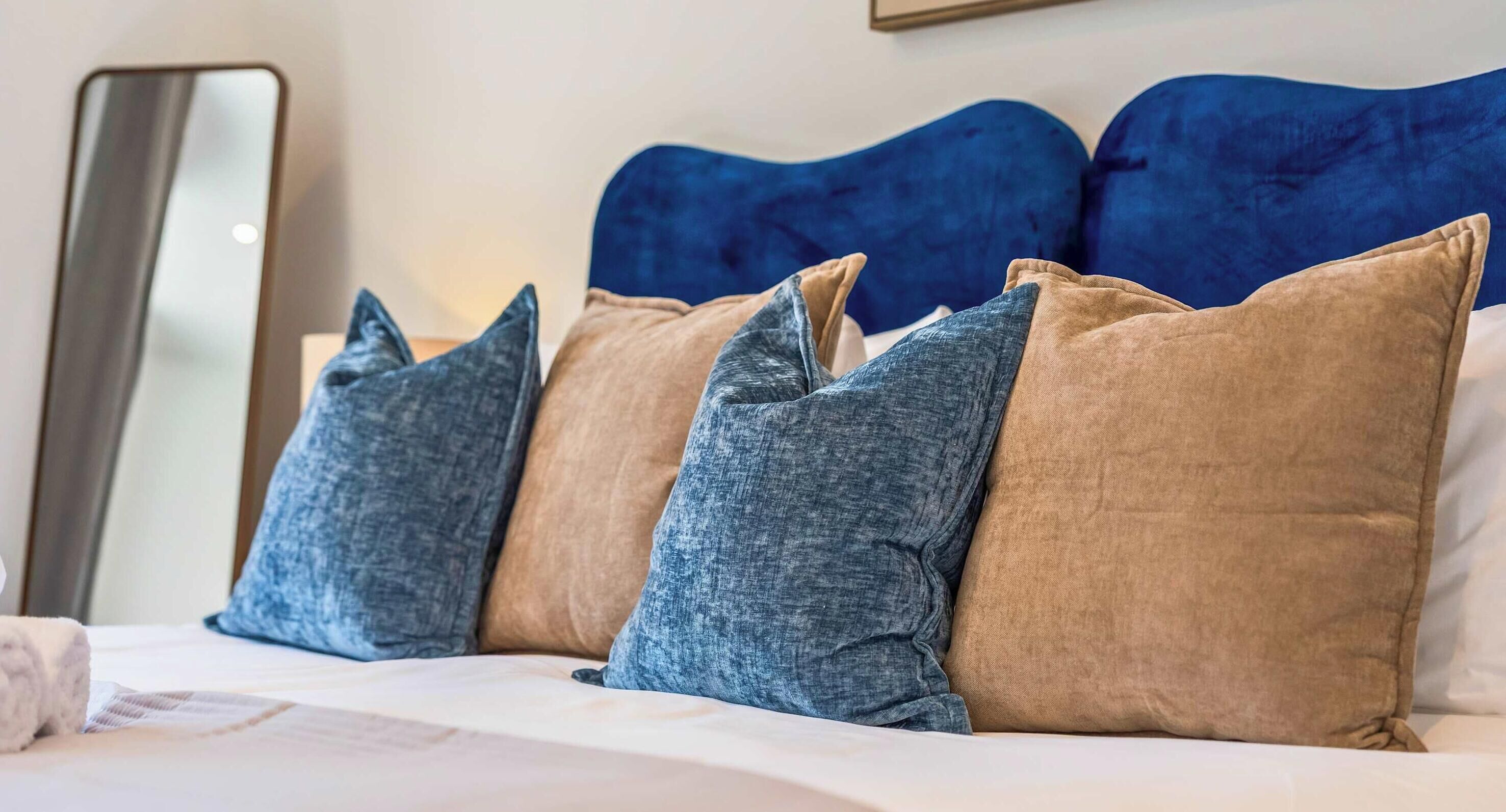 A bed with a headboard, pillows, and a bedside table.
