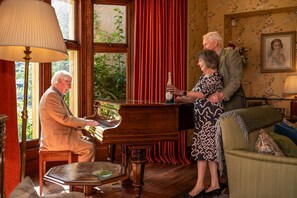 A room with a grand piano, a dining table, and a sofa.