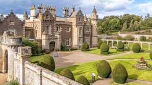 A historic building with a formal garden, including topiary and a bridge.