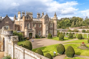 Un bâtiment historique doté d’un jardin à la française, comprenant des éléments de jardinage ornemental et un pont.
