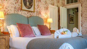 A hotel room with a bed, pillows, a bedside lamp, a mirror, and a door.