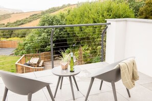 A balcony with a table and chairs, a bottle of wine, and a plant.