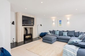 A modern living room with a sectional sofa, a fireplace, and a flat-screen TV.