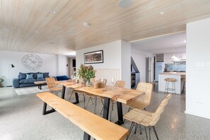 Een modern interieur met een eethoek, bestaande uit een houten tafel, stoelen, een bank en een grote wandklok.