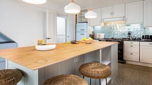 Una cocina moderna con armarios blancos, una isla de madera e iluminación colgante.