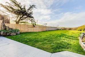A well-maintained lawn with a wooden fence and a paved walkway.