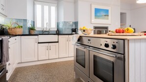 Una cocina moderna con armarios blancos, electrodomésticos de acero inoxidable y una ventana con persianas.
