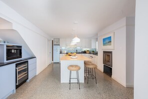 Een moderne keuken met een centraal eiland, barkrukken en een inbouwoven.
