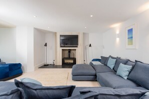 Een moderne woonkamer met een modulaire bank, een flatscreen televisie, een open haard en een groot raam.