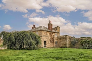 A historic stone building with a large arched doorway, a chimney, and a solar panel on the roof.
