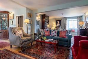 A living room with a sofa, armchair, and a coffee table with decorative items.