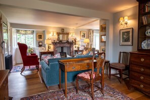 A traditional living room with a fireplace, a red armchair, a blue sofa, and a wooden coffee table.