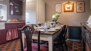A dining area with a table set for four, chairs, a radiator, and a refrigerator.