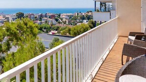 A balcony with a view of the sea and buildings, furnished with wicker chairs and a table. - Apartment Limoncello (Sant Pere de Ribes)