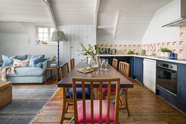 A dining area with a wooden table, chairs, and a vase of flowers.
