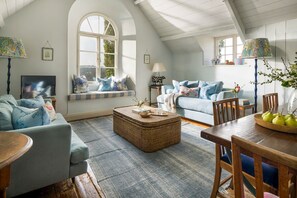 Un salon chaleureux avec un plafond haut, une grande fenêtre et un coin salon confortable.