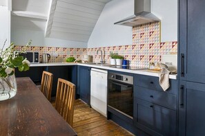 A kitchen with a wooden dining table, a dishwasher, an oven, and a microwave.