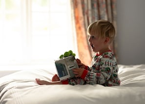 A child sitting on a bed reading a book with a window in the background. - Lostwithiel House - Three Bedroom Villa, Sleeps 6 (Boconnoc)