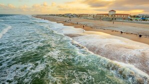 A beach with waves, a promenade, and buildings in the background. - LUX Mins to St George St - Anastasia Beach - Flagler Hospital - Sunrise (St. Augustine)