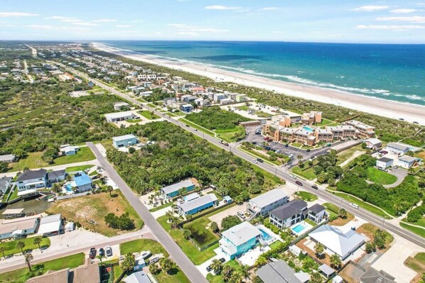 An aerial view of a coastal residential area with houses, roads, and a beach.