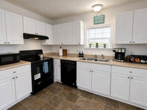 A kitchen with white cabinets, a black stove, a dishwasher, and a coffee maker.