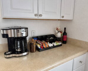 Eine Küchenarbeitsplatte mit Kaffeemaschine, Gewürzregal, einer Weinflasche und einem dekorativen Gegenstand.