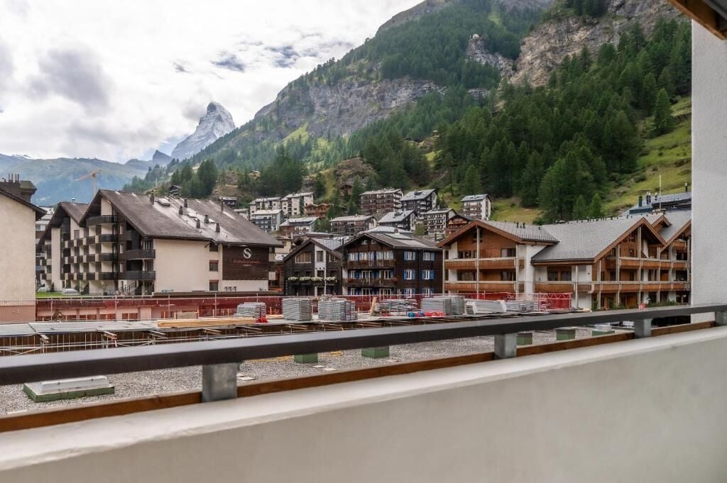 A mountain town with traditional buildings, a prominent mountain peak, and construction in the foreground.