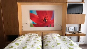 A room with two beds, a desk, a television, and a wall-mounted speaker. - Victoria B Studio - InspiringPlaces  (Zermatt)