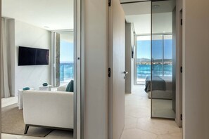 A modern hotel room with a large sliding glass door leading to a balcony with a sea view. - New Penthouse with Pool and Beach, with 4 Bedrooms (Golfo Aranci)