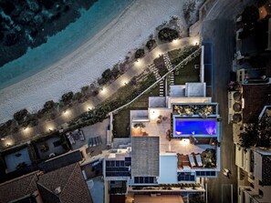 A modern house with a swimming pool, outdoor seating, and a beach view. - New Penthouse with Pool and Beach, with 4 Bedrooms (Golfo Aranci)