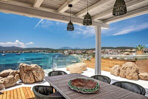 A terrace with a view of a coastal town, a pool, and outdoor seating. - New Penthouse with Pool and Beach, with 4 Bedrooms (Golfo Aranci)