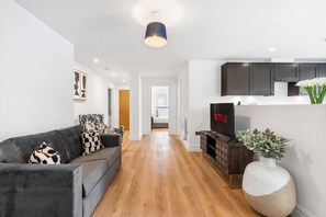 Ein modernes Wohnzimmer mit einer Couch, einem Fernseher, einem Schrank und einer großen Vase.