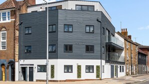 Um edifício moderno com telhado plano, várias janelas e uma varanda.