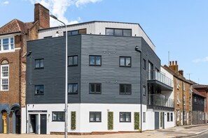 Ein modernes Gebäude mit flachem Dach, zahlreichen Fenstern und einem Balkon.