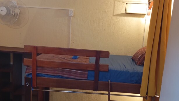 A bunk bed with a desk and chair, a small table with a rolled-up mat, and a ladder.