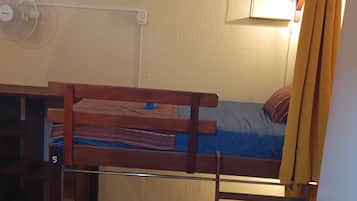 Een stapelbed met een bureau en stoel, een tafeltje met een opgerolde mat, en een ladder.