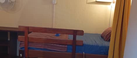 A bunk bed with a desk and chair, a small table with a rolled-up mat, and a ladder.